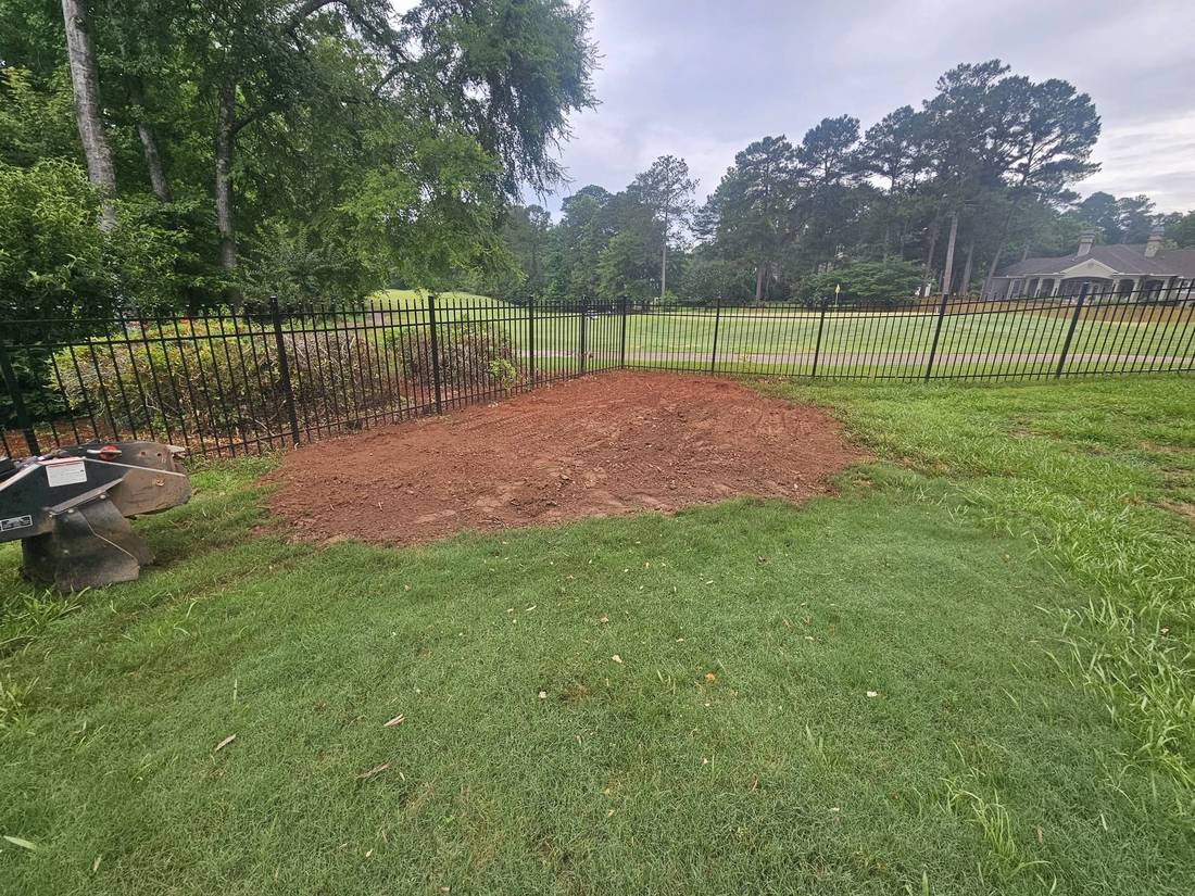 Ground and raked area along a fence next to a golf course
